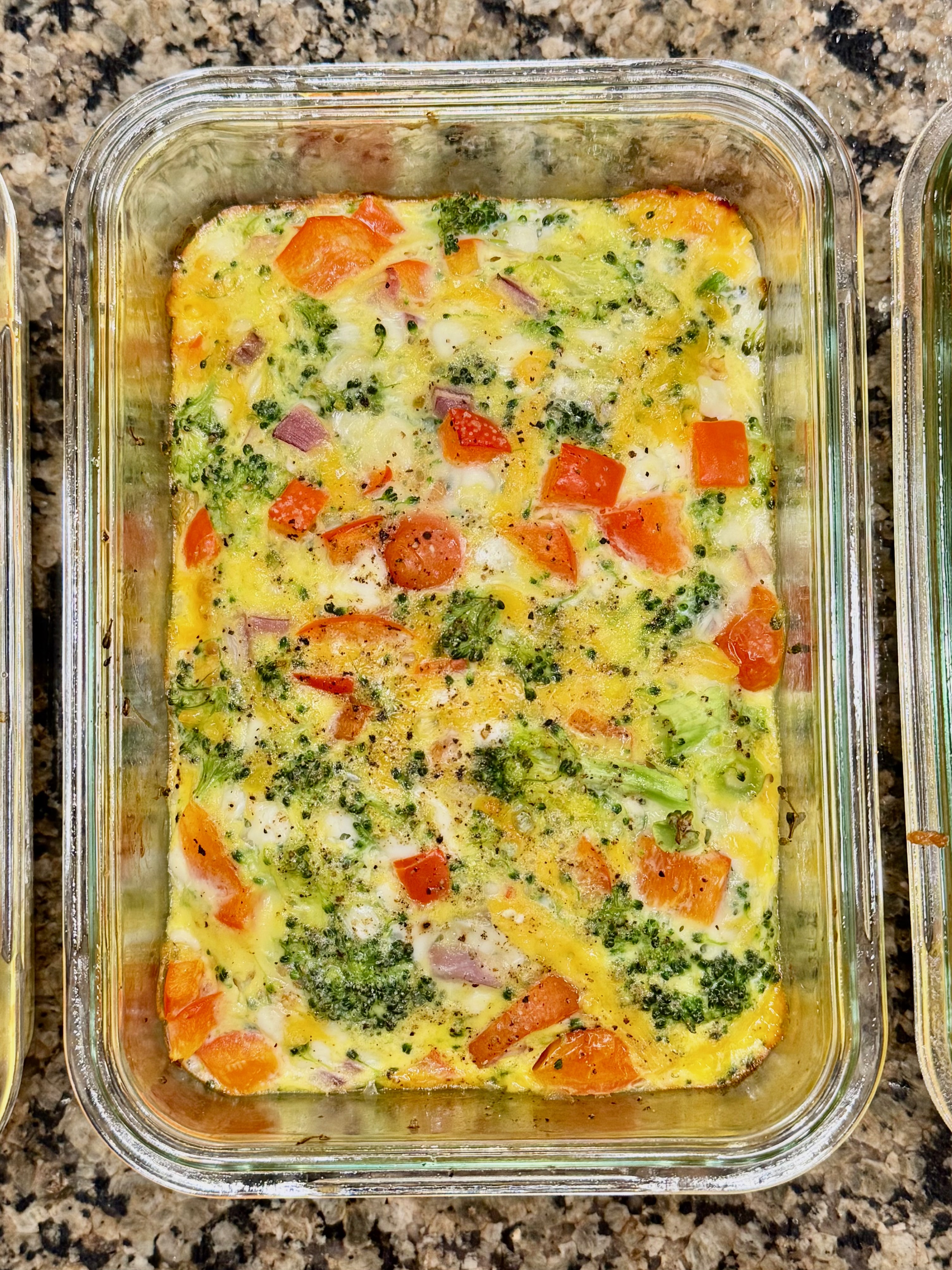 A cheesy veggie egg bowl filled with scrambled eggs, melted cheese, and vegetables, served in a glass dish