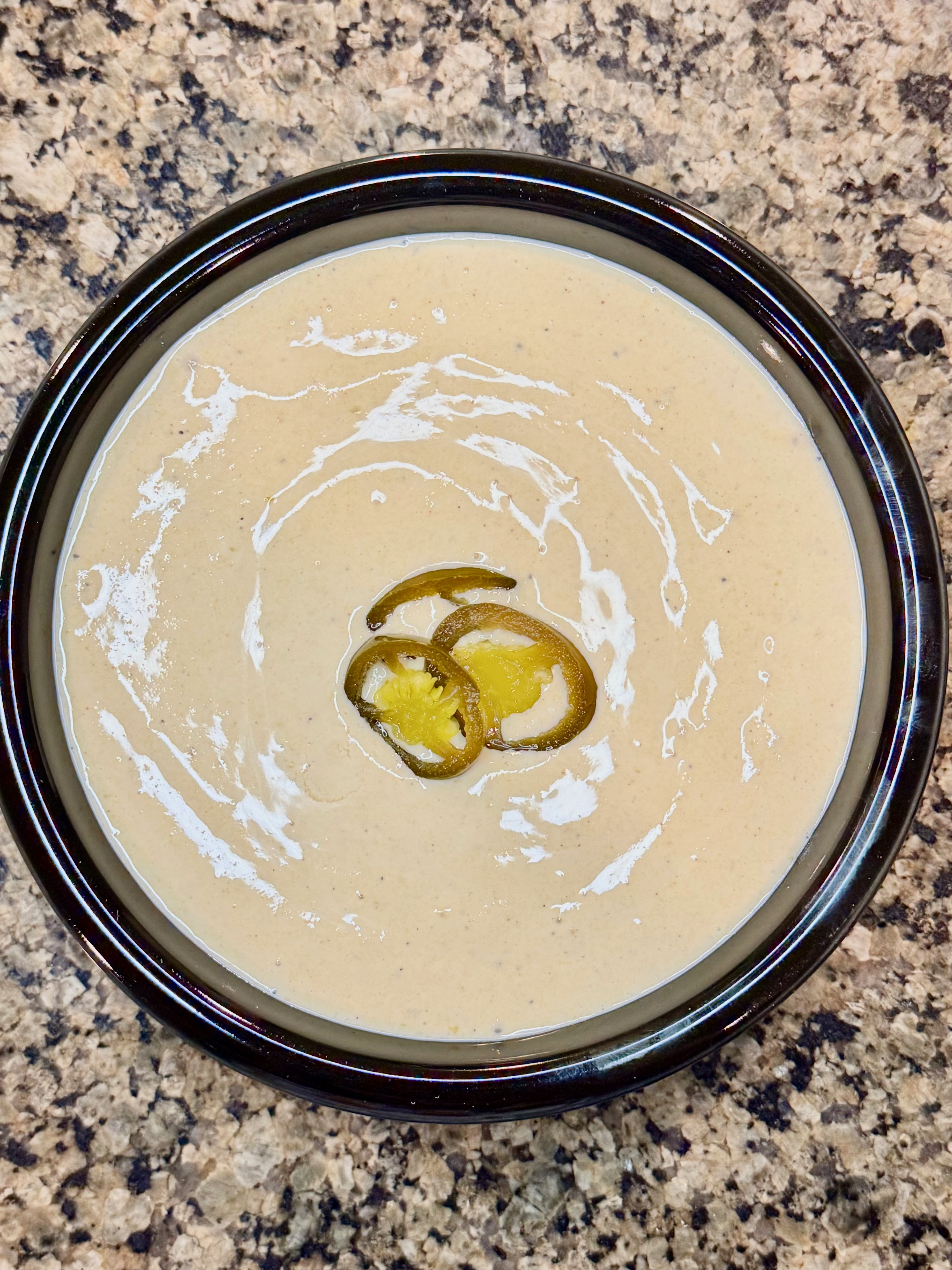 A bowl of creamy cottage cheese queso, topped with jalapeños.