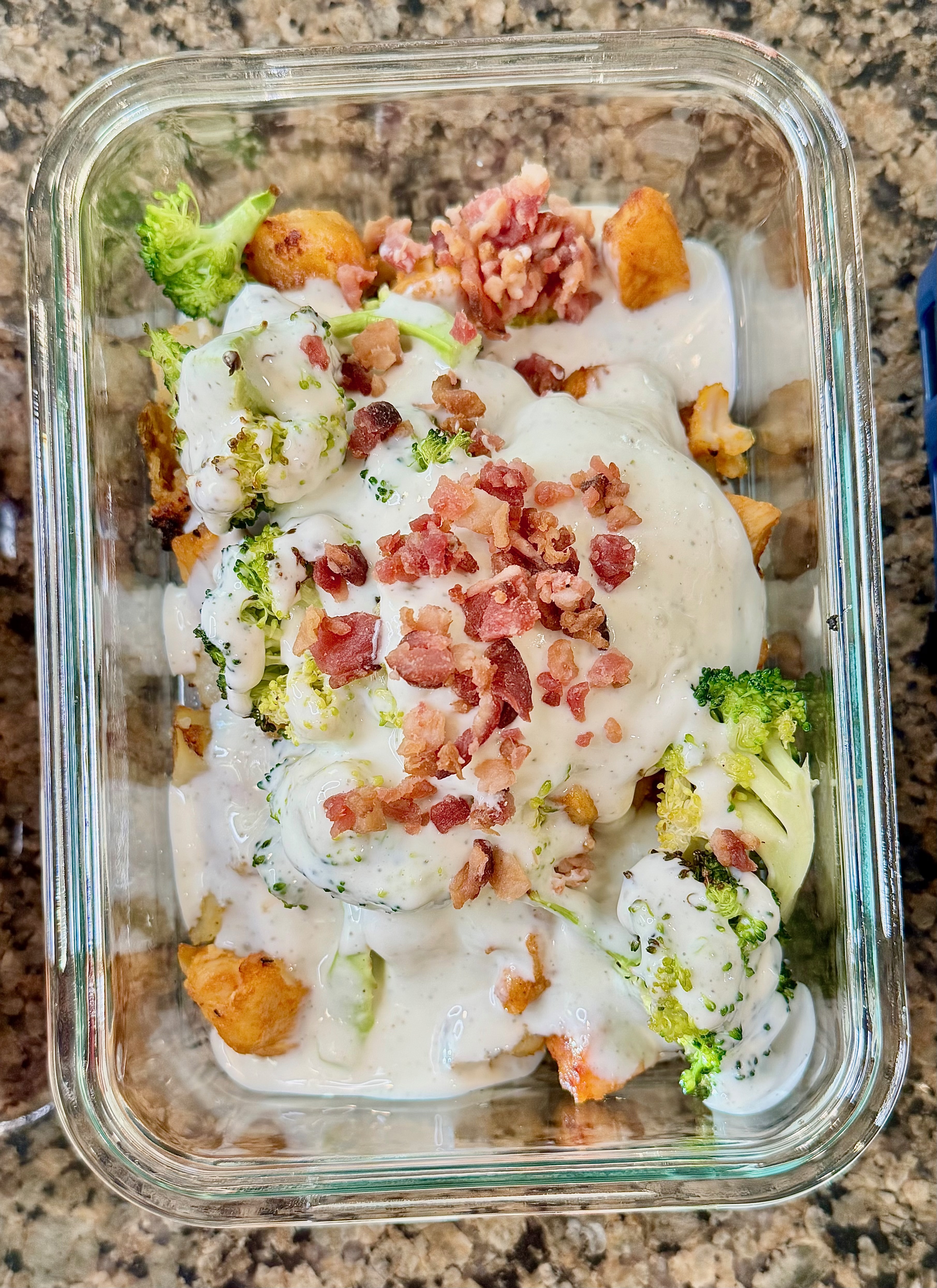A chicken bacon ranch bowl with roasted potatoes, crispy bacon, and a creamy cottage cheese ranch dressing, served in a glass dish.