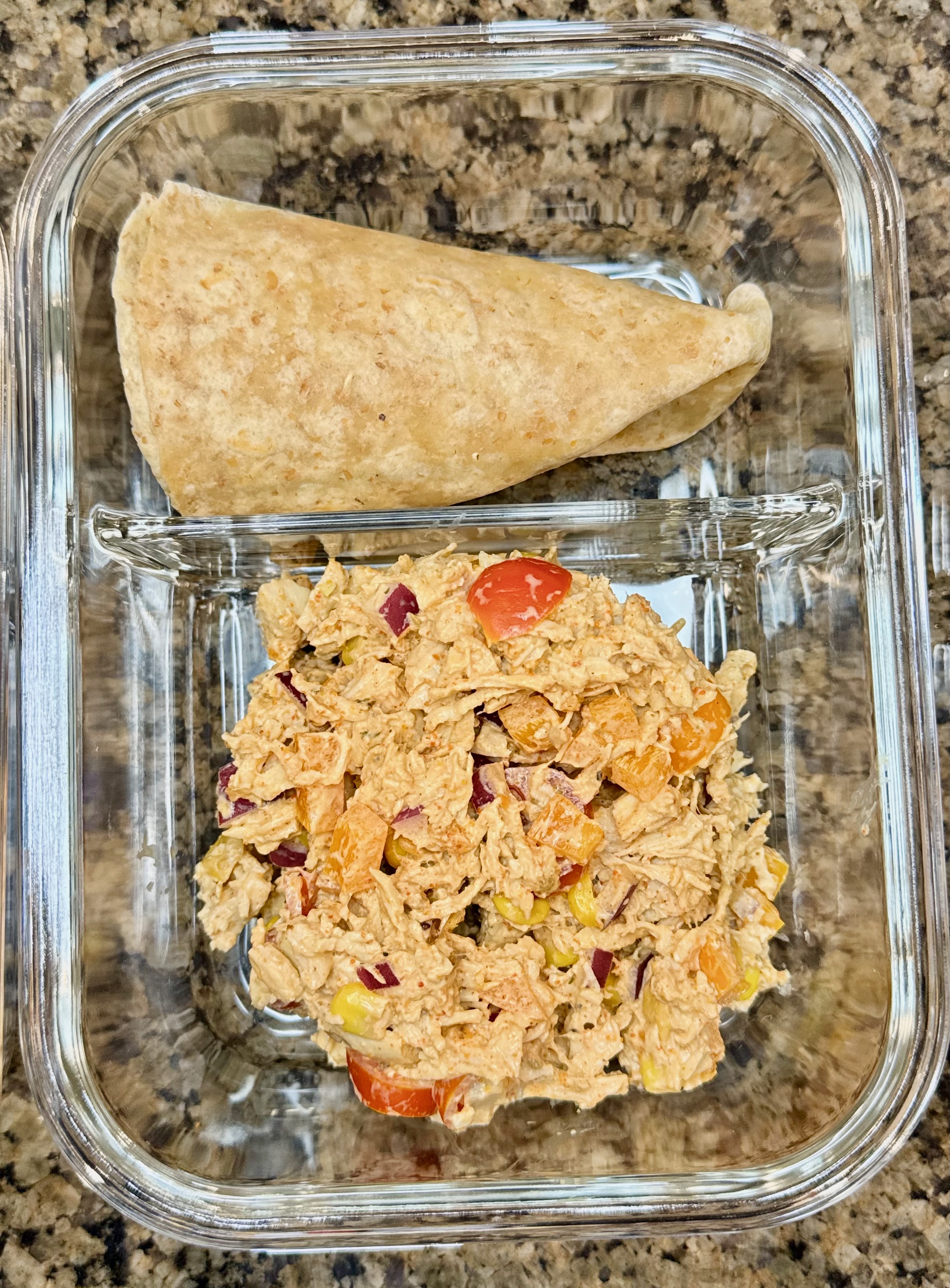 Taco chicken salad with chicken, corn, tomatoes, and a creamy taco dressing served in a glass two section bowl.